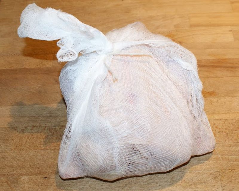 The stuffed chicken is wrapped in a layer of cheesecloth.