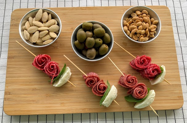 The appetizer cours - nuts, olives, and skewers with salami, basil and goat cheese