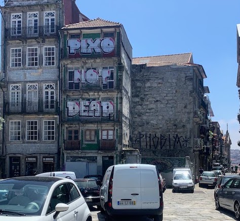 A building with the words "PIXO NOT DEAD" written on the wall