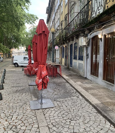 Early morning scene in Porto - cafe lights on, umbrellas folded, chairs and tables stacked