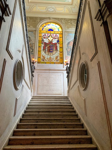 The stairway at Palácio Chiado with stained glass window at the top