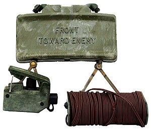 A Vietnam-era Claymore mine (rear), with firing device (front left) and electric blasting cap (front right).