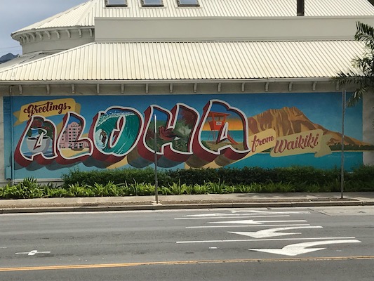 A mural with the greeting "Aloha from Waikiki" on a building in Hawaii.
