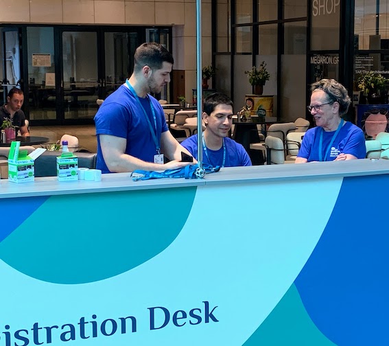 Mary and two other volunteers working the registration desk at WordCamp Europe 2023 in Athens.