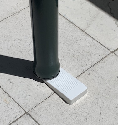 A small doorstop wedged under the leg of an outdoor table.