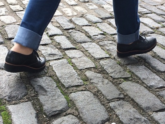 A picture of a person's feet walking across cobblestones.