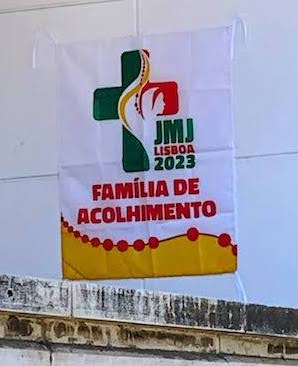 A sign outside an apartment announces "Família Acolhimento" or "Family Reception", indicating that a family is hosting pilgrims for World Youth Day.