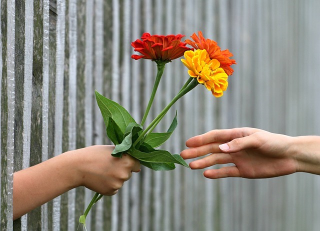 An unseen person handing a small bouquet of flowers to another unseen person.