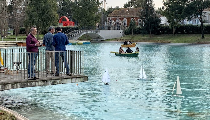 Men sailing radio-controlled sailboats in the lake at Jardim Mário Soares in Lisbon.