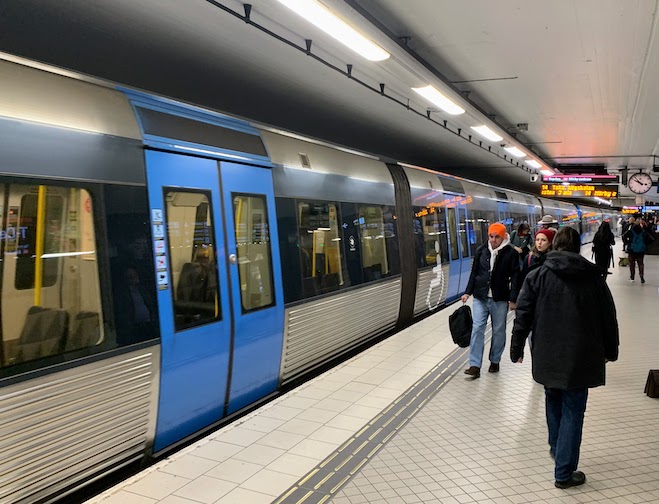 Inside a brightly lit Stockholm metro station, looking at a clean, modern train.