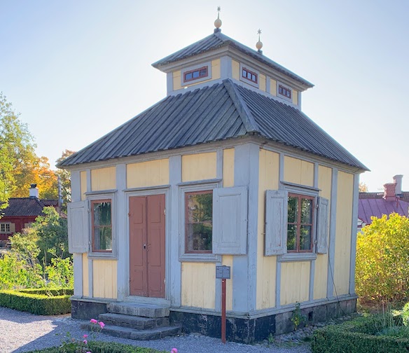 A small building with yellow sides and grey trim at Skansen.