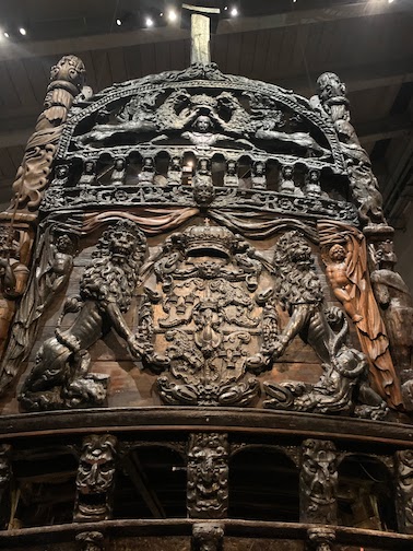 A view of the elaborate carvings on the stern (rear) of the ship. In the center two lions are holding the royal coat of arms of the Vasa dynasty. At the top, two griffons hold the crown over the head of young king Gustav Adolf.