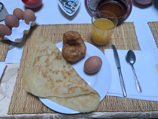 Breakfast - a thin crepe, a sweet pastry, a hard-boiled egg and orange juice.