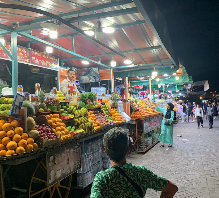 Mary looking at fruit stands in the Marrakech medina at night.