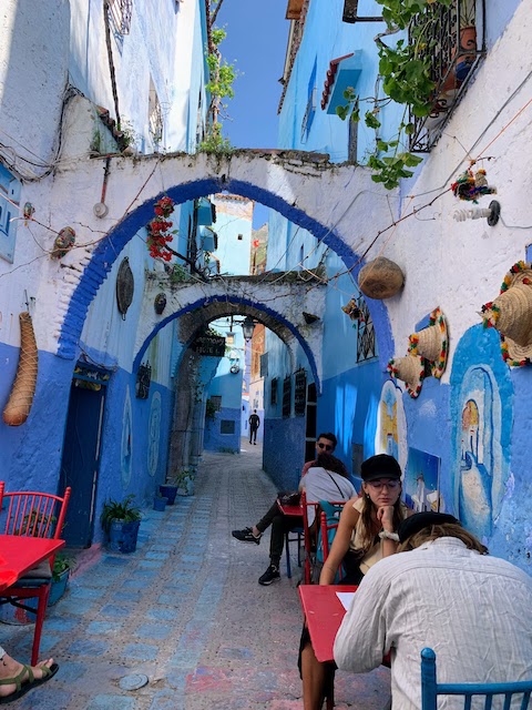 A narrow street in Chefchaouen with tables for a cafe.