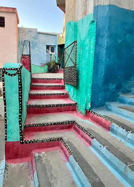 A stairway in Moulay Idriss. The walls are painted bright green and blue. The stairs are painted red and blue.