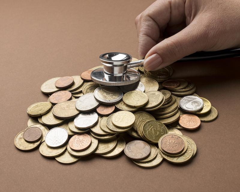 A stethoscope on top of a pile of coins