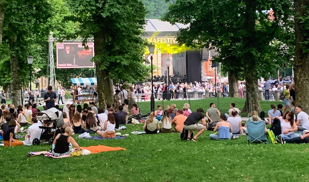 Concert goers sitting on blankets and folding chairs in Park Zvezda