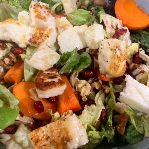 A close up photo of a persimmon, halloumi, and walnut salad.