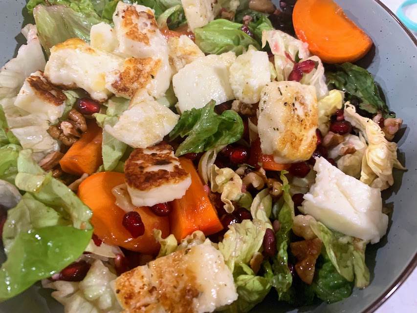 A close up photo of a persimmon, halloumi, and walnut salad.