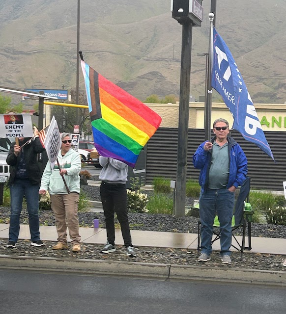 A woman with a pride flag stands next to a man with a Trump flag at the April 19 Day of Protest rally in Clarkston, WA.
