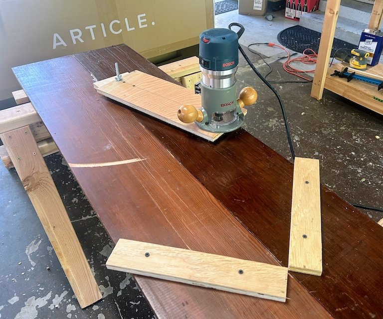 The jig I built to cut the curves in the corner shelves. The router pivots across a shelf clamped into place.