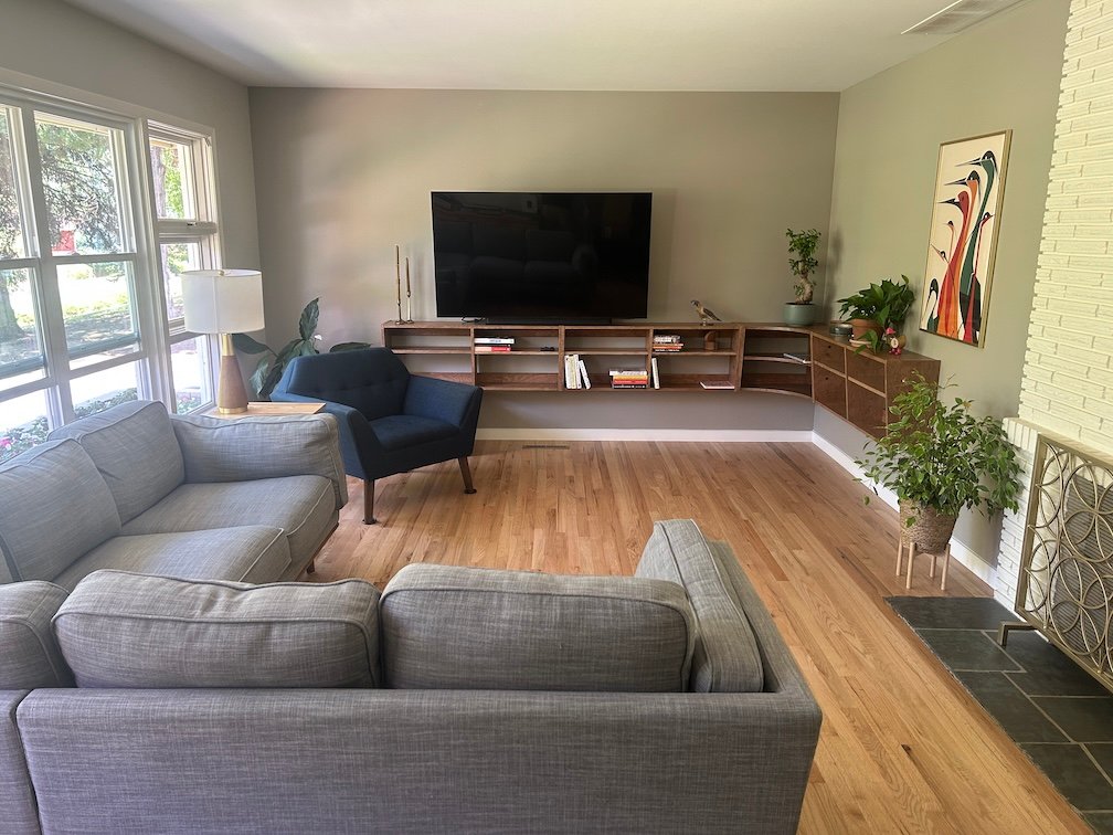 Our living room in August, 2025, with furniture, a tv, and the new shelves installed.