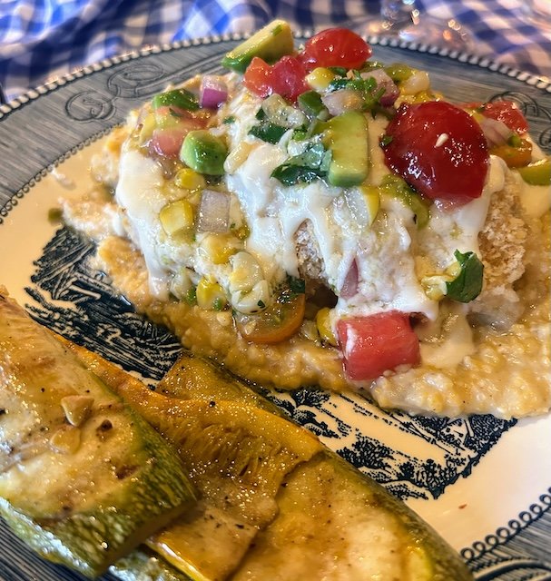 An entree - Stuffed chicken breast with a roasted poblano cream sauce, served with green chili cheese grits and grilled local squash.